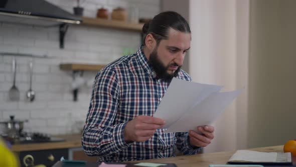 Dissatisfied Angry Middle Eastern Man Tearing Documents Thinking in Home Office