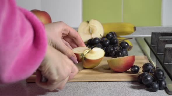 Woman Hands Cut an Apple on a Plank With a Knife