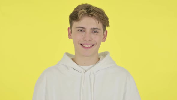 Young Man Shaking Head As Yes Sign on Yellow Background