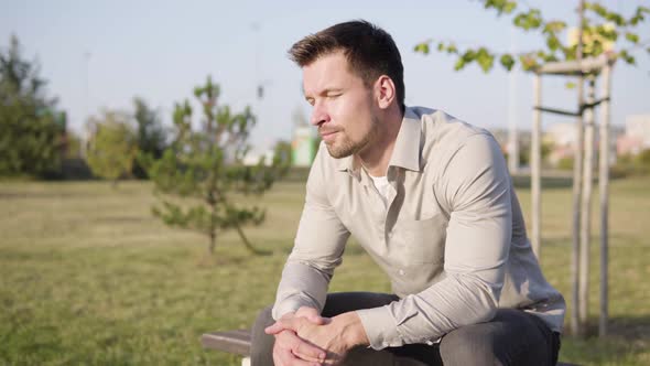 A Young Caucasian Man Relaxes and Enjoys the Sun with Closed Eyes As He Sits in a Park