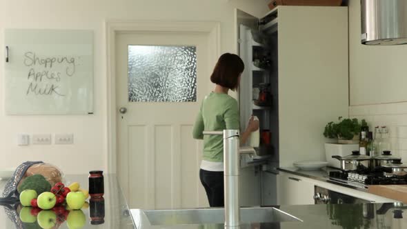 Woman in kitchen putting groceries away