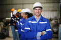 Young confident leader of team standing in front of factory workers - PhotoDune Item for Sale