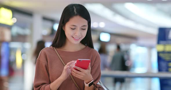 Woman check on the discount in mobile phone inside shopping plaza