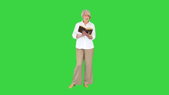 Beautiful Senior Woman Reading Aloud From a Book on a Green Screen Chroma Key