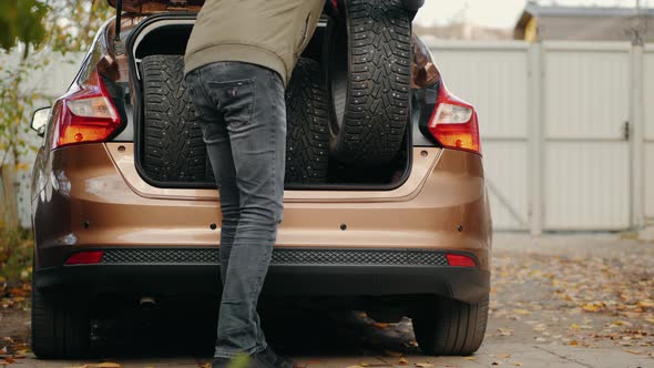 A Man Unloads Winter Tires From a Car Trunk