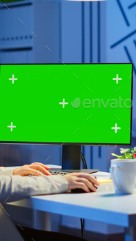 Businesswoman looking at green screen monitor of computer