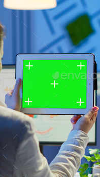 Businesswoman holding tablet with green screen monitor