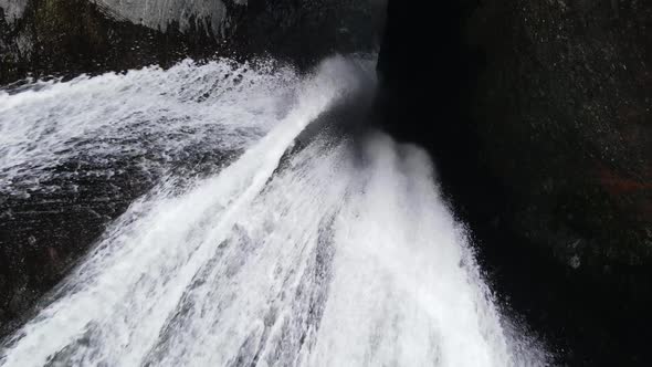 Top-down drone footage of a waterfall in a tight canyon in the Cirque of Mafate at the Reunion islan