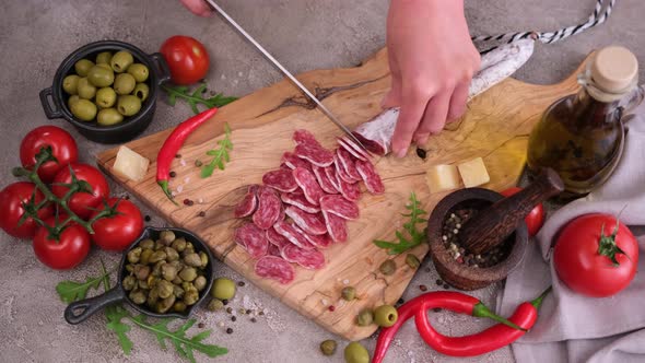 Woman Slicing Fuet Sausage with Knife at Domestic Kitchen