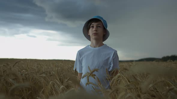 Boy Stands in a Field at the Beginning of a Thunderstorm, Strong Wind, Rain