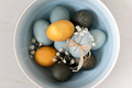 Baby blue, yellow and dark grey Easter eggs in a bowl, top view. Festive decoration. - PhotoDune Item for Sale