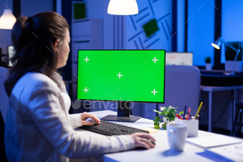 Businesswoman looking at green screen monitor of computer