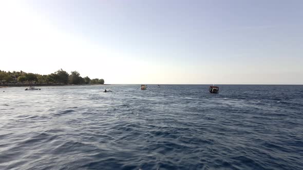 Tourist boats driving on indian ocean towards sunset.Aerial forward drone shot.Bali,Indonesia.