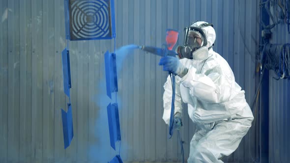 Expert Is Using a Spraying Gun To Paint Metal Pieces at a Painting Factory Facility