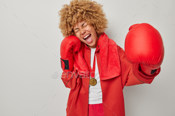 rst place on championship dressed in red uniform and boxing gloves achieves great results in sport field poses indoor against grey background