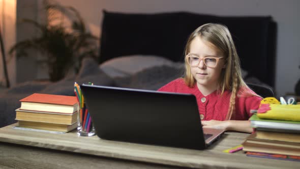 Smiling School Girl Surfing Net on Laptop at Home