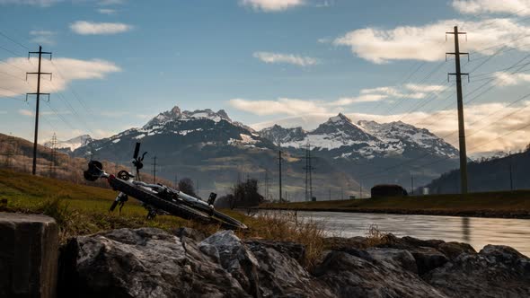 Time lapse ofing clouds over the snow capped mountains standing high besides a river. Low angle.