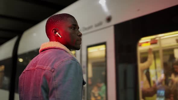 Black man in denim jacket waiting subway car