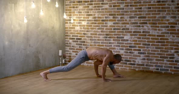 Male Gymnast Is Training Alone in Room, Standing on One Leg and Hand, Holding Body