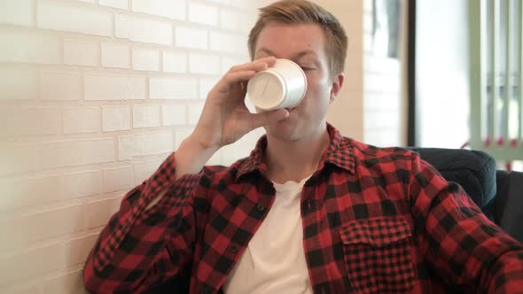 Young Thoughtful Hipster Man Smiling And Drinking Coffee