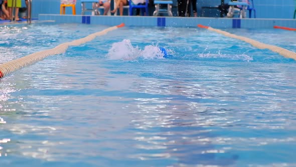 Professional Young Swimmer in Blue Cap Swims in Pool