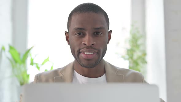 Close Up of African Man with Laptop Smiling in Camera