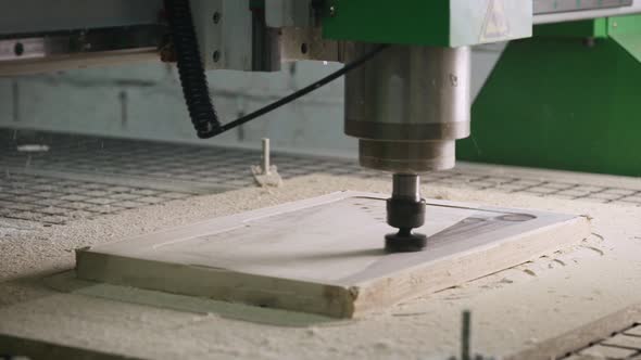 The CNC Machine Cuts a Piece of Wood with a Milling Cutter