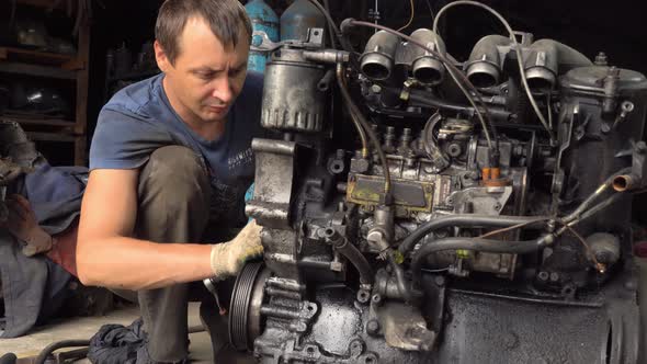 auto mechanic checks internal combustion engine. engine is covered in oil dirty