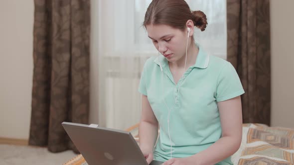 Studen girl with a serious look studying with distant teacher remote communication via laptop.