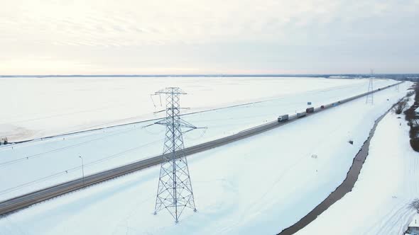 Aerial View Over Power Lines with Towers Near Road with Traffic in Winter