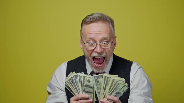 Happy senior man holding many dollar banknotes