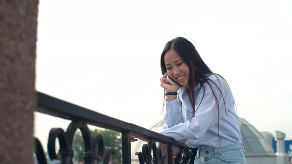 Happy Asian Lady Chatting on Phone at Summer Day Outdoors