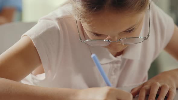 Close Up of the Female Pupil Wearing Glasses Doing Test and Filling Answers 