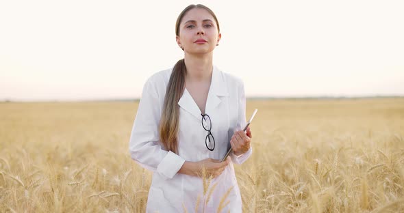 Worker Posing in Middle of Wheat Field at Sunset