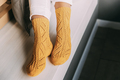 Close up of female legs in yellow knitted winter socks, white trousers resting sitting on a bench at - PhotoDune Item for Sale