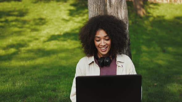 Darkskinned Woman with Afro Hairstyle Headphones on Neck