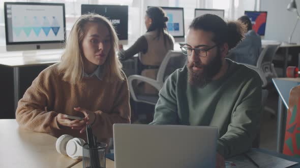 Two Young Colleagues Working Together in Office