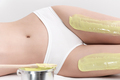Legs of slim woman while she lying down on couch during depilation process with green hot wax - PhotoDune Item for Sale