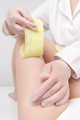 Depilation procedure - cosmetologist hands in gloves removing hair on women leg. Waxing process - PhotoDune Item for Sale