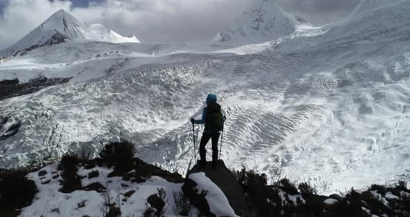 Woman backpacker hiking on winter mountain looking the glacier view