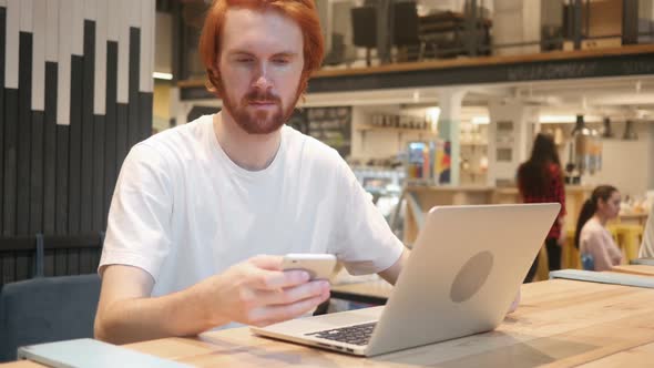 Redhead Beard Man Using Smartphone in Cafe Typing SMS