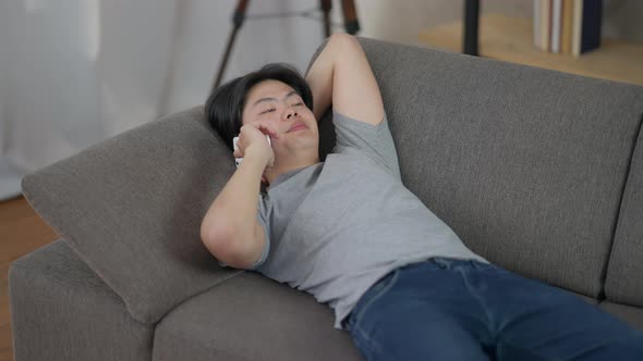 Portrait of Confident Serious Man Lying on Couch Talking on the Phone