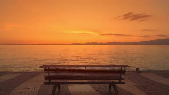 Wooden Bench Installed on City Waterfront Against Lake Garda