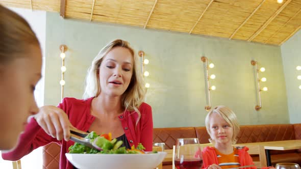 Mother serving salad to her daughter in restaurant 4k