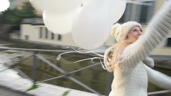 Slow motion young beautiful blonde woman running holding balloons