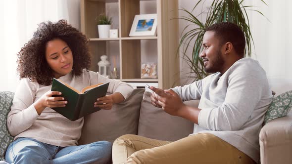 Happy Couple with Smartphone and Book at Home