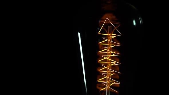 Vintage Light Bulb Incandescent Filament Close Up Macro with Black Background.