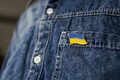 Ukrainian flag icon is pinned on blue jeans jacket. Support for Ukraine. War in Ukraine. - PhotoDune Item for Sale