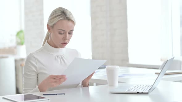 Young Businesswoman Reading Documents in Modern Office