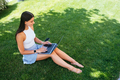 Young girl works with a laptop, sitting on the lawn. - PhotoDune Item for Sale